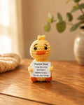Tiny yellow crochet duck holding an affirmation card